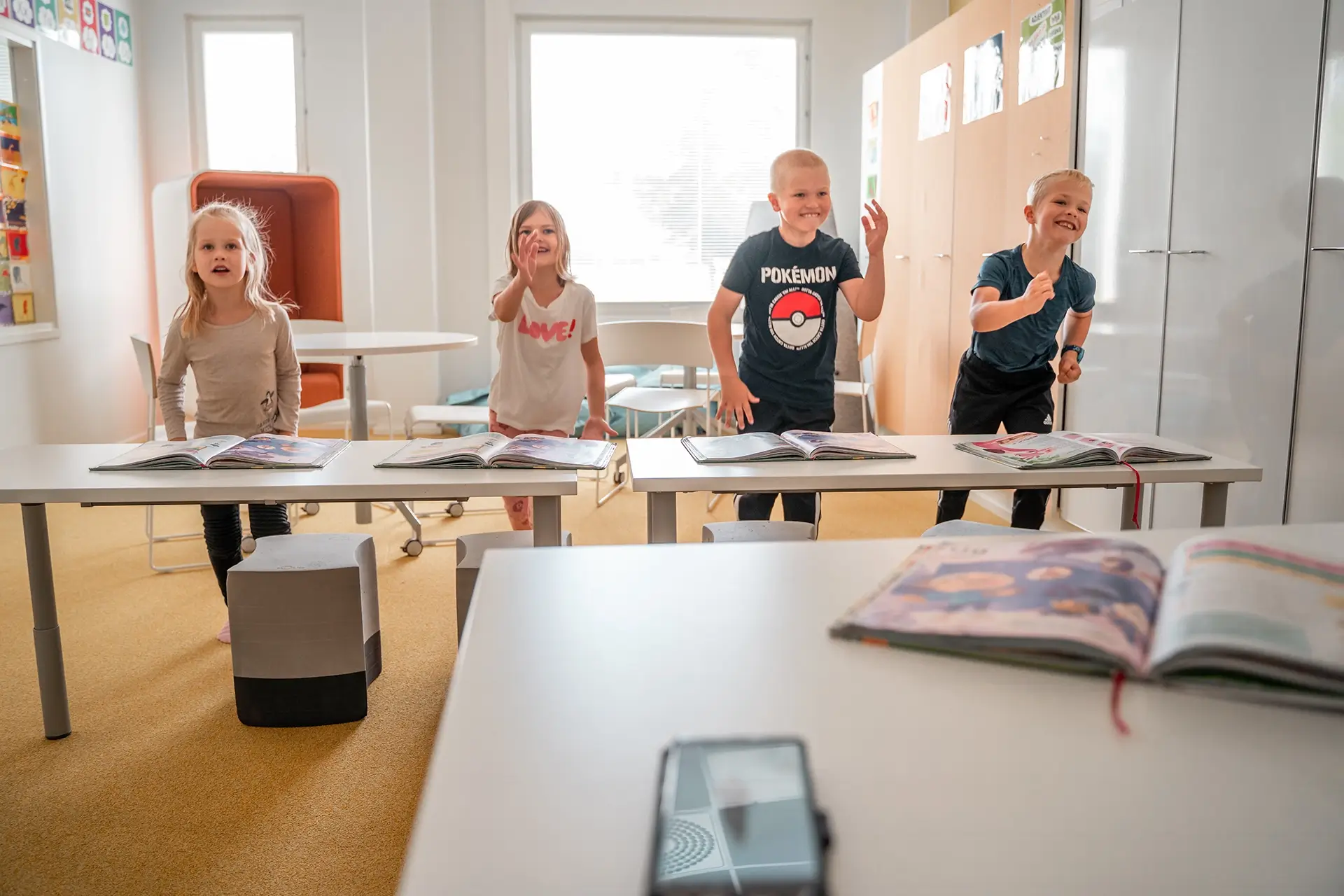 Teacher in a classroom with a laptop and students in the background