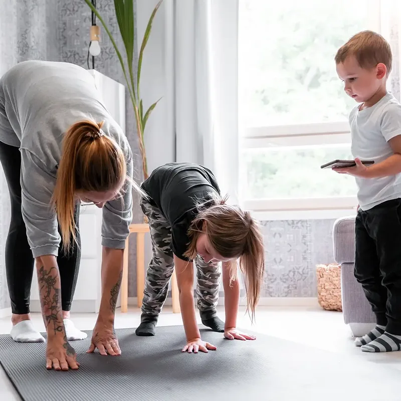 A mother and her children doing an exercise together in the living room